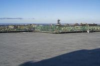 an empty parking lot with clear glass walls and pavement in the foreground, overlooking an urban setting