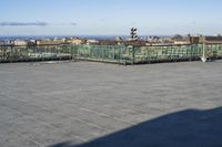 an empty parking lot with clear glass walls and pavement in the foreground, overlooking an urban setting