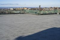 an empty parking lot with clear glass walls and pavement in the foreground, overlooking an urban setting