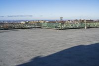 an empty parking lot with clear glass walls and pavement in the foreground, overlooking an urban setting