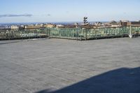 an empty parking lot with clear glass walls and pavement in the foreground, overlooking an urban setting