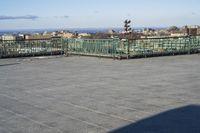 an empty parking lot with clear glass walls and pavement in the foreground, overlooking an urban setting