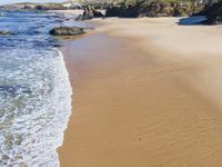 a beach with several small waves and white sand in front of it and some blue sky