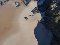 a beach that has sand in the middle and very large rocks in the middle of it