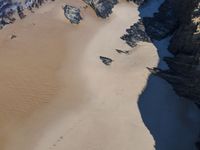 a beach that has sand in the middle and very large rocks in the middle of it