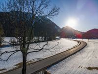 there is snow on the ground in front of the mountains and village with sun shining over the city