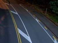 two white arrows painted on a black road at night time with one white and one yellow