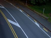 two white arrows painted on a black road at night time with one white and one yellow