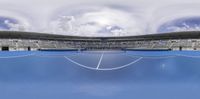 a tennis court with several empty stands in it and clouds overhead them at the ball