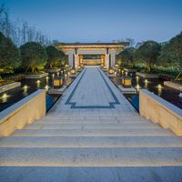 stone steps leading to a very large building in a garden, lit up at night