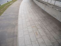 this walkway runs on the side of a river, and is beside a concrete fence