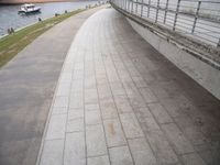 this walkway runs on the side of a river, and is beside a concrete fence