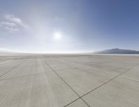 an empty air field, with mountains in the background and a sky filled with clouds