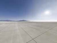 an empty air field, with mountains in the background and a sky filled with clouds