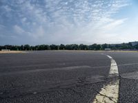 there is an empty airport parking lot with no cars on it and a stop sign on the end