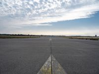 airplane landing strip on empty airport runway with yellow lines coming out of the air and clouds in the distance