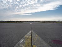 airplane landing strip on empty airport runway with yellow lines coming out of the air and clouds in the distance