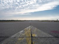 airplane landing strip on empty airport runway with yellow lines coming out of the air and clouds in the distance