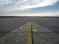 airplane landing strip on empty airport runway with yellow lines coming out of the air and clouds in the distance