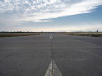 airplane landing strip on empty airport runway with yellow lines coming out of the air and clouds in the distance