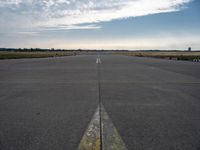 airplane landing strip on empty airport runway with yellow lines coming out of the air and clouds in the distance