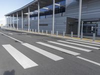 the empty streets of a very wide airport terminal building with a clear blue sky in the background