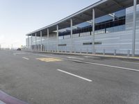 the empty streets of a very wide airport terminal building with a clear blue sky in the background