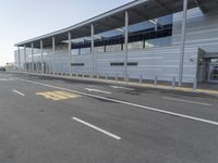 the empty streets of a very wide airport terminal building with a clear blue sky in the background