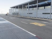 the empty streets of a very wide airport terminal building with a clear blue sky in the background