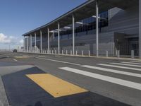 the empty streets of a very wide airport terminal building with a clear blue sky in the background