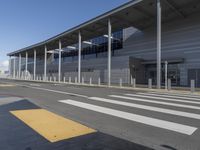 the empty streets of a very wide airport terminal building with a clear blue sky in the background