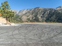 an empty asphalt parking lot with mountains in the background of it, and a blue sky overhead