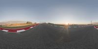 a 360 lens view of an empty asphalt race track at sunset with clouds in the sky