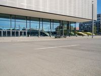 the empty asphalt road passes through a building with tall glass walls and stairs leading to the door