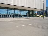 the empty asphalt road passes through a building with tall glass walls and stairs leading to the door