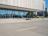 the empty asphalt road passes through a building with tall glass walls and stairs leading to the door