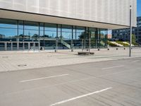 the empty asphalt road passes through a building with tall glass walls and stairs leading to the door