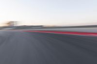 the red trim of an empty track with blurry image of an orange racer in motion