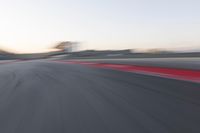 the red trim of an empty track with blurry image of an orange racer in motion