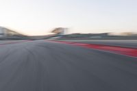 the red trim of an empty track with blurry image of an orange racer in motion