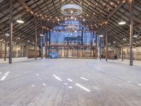 an empty barn with wood and string lights in the ceiling of it, and a stage in the center that's ready to be used for the stage