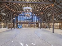 an empty barn with wood and string lights in the ceiling of it, and a stage in the center that's ready to be used for the stage