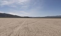 an empty barren area with some mountains in the background at death valley national park, death valley national park