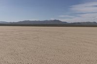 an empty barren area with some mountains in the background at death valley national park, death valley national park