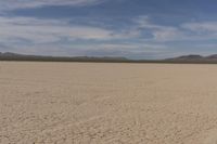 an empty barren area with some mountains in the background at death valley national park, death valley national park