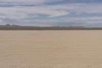 an empty barren area with some mountains in the background at death valley national park, death valley national park