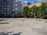 an empty basketball court is seen in this photograph from the corner in front of an apartment complex