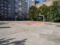 an empty basketball court is seen in this photograph from the corner in front of an apartment complex