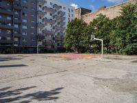 an empty basketball court is seen in this photograph from the corner in front of an apartment complex