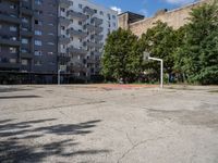 an empty basketball court is seen in this photograph from the corner in front of an apartment complex